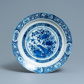 Un plat en faïence de Delft en bleu et blanc à décor d'un paon dans un jardin chinois, daté 1693