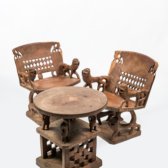 An African wooden salon set comprising two chairs and a coffee table, 20th C.