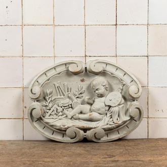 A white-patinated oval wood carving with a putto holding a painter's palette, 18th C.