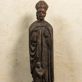 A large wooden sculpture of Saint Nicolas with a kneeling boy, 17th C.