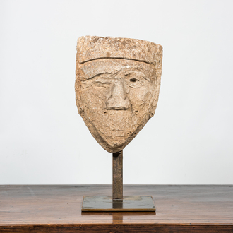 A large carved stone head of a winking man, 15th C. or later