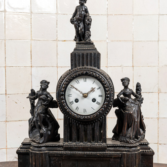 An ebonised mantel clock with romantic figures and topped with a putto, 19th C.