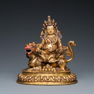 A Tibetan gilt bronze group of Jambhala on his lion, 19/20th C.