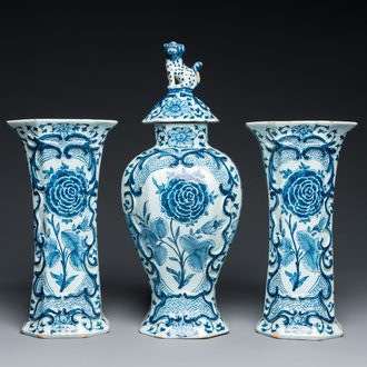 A Dutch Delft blue and white garniture of three vases with a large rose, 18th C.