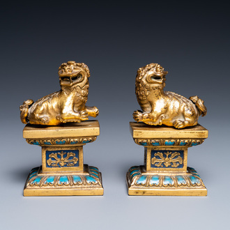 A pair of Chinese gilt copper alloy Buddhist lions on champlevé enamel bases, 19th C.