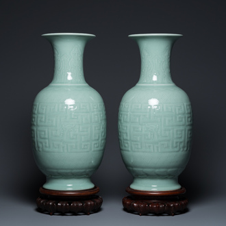 A pair of Chinese monochrome celadon-glazed vases with underglaze design on wooden stands, Qianlong mark, 18/19th C.