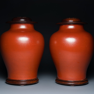 A pair of Chinese monochrome coral-red-glazed vases with wooden stands and lids, Republic