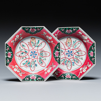 Een paar Chinese octagonale famille rose borden met robijnrode fondkleur, Yongzheng