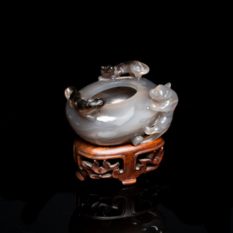A Chinese agate water pot with Buddhist lions on a carved wooden stand, 19th C.