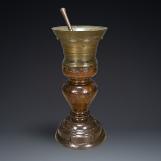 A large French bronze mortar and pestle on its carved oak base, dated 1631