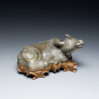 A Chinese monochrome brown-grey-glazed sculpture of a reclining water buffalo on wooden stand, 19th C.