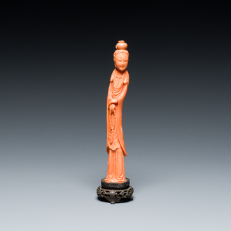 A Chinese red coral figure of a standing lady holding a court necklace, 19/20th C.