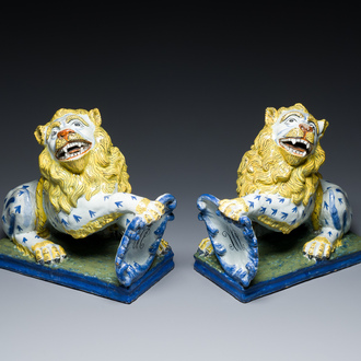 A pair of polychrome French faience lions holding a monogrammed shield, probably Rouen, 18/19th C.