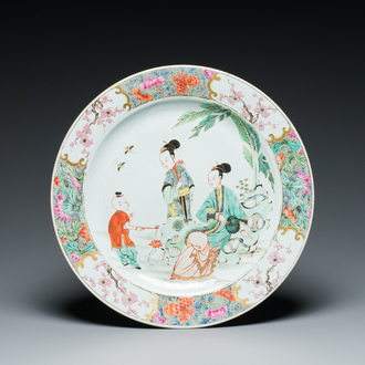 A Chinese famille rose dish with two ladies and a boy in a garden, Yongzheng