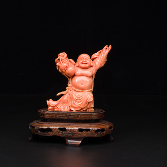 A Chinese red coral figure of a laughing Buddha on wooden stand, 19/20th C.