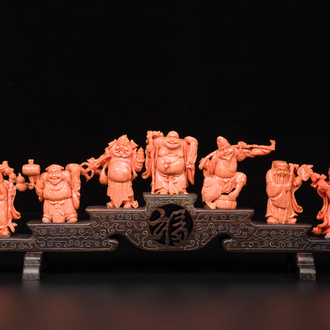 A set of seven Chinese red coral figures on wooden stand, 19/20th C.