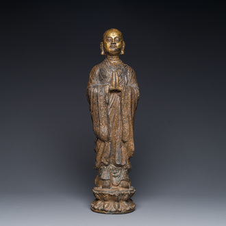 Een Chinese vergulde gietijzeren figuur van een staande monnik, Ming