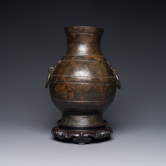 Een Chinese bronzen 'hu' vaas met Han-stijl taotie handgrepen op houten sokkel, Ming