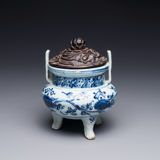 A Chinese blue and white tripod censer with floral design and a wooden cover, Ming