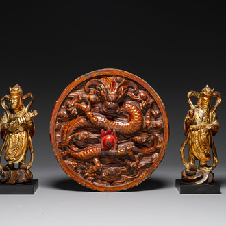 A pair of Chinese gilt-lacquered wooden guardians and a round 'dragon' plaque, 19th C.