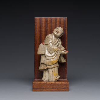 A Chinese partly polychromed soapstone figure on a wooden stand, 18th C.