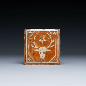 A slip-decorated lead-glazed tile with a stag's head and a star, Flanders or France, 15/16th C.