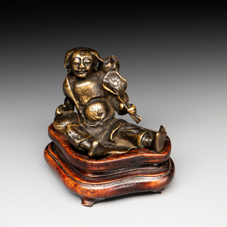 A Chinese bronze paperweight in the form of 'Shi De 拾得' on wooden stand, 16th C.