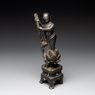 A Chinese bronze incense holder of a boy standing on a lotus, Ming