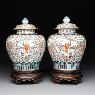 A pair of Chinese famille rose covered vases with figural design and wooden stands, 19th C.