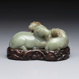 A Chinese celadon jade group of three goats on wooden stand, 19/20th C.