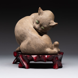 A Chinese Shiwan stoneware cat on a wooden stand, 20th C.