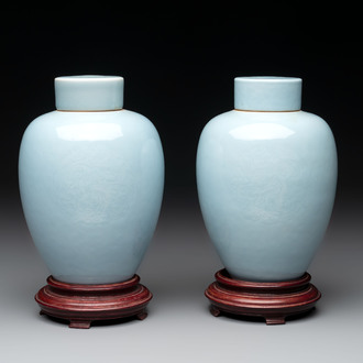 A pair of Chinese claire-de-lune jars and covers on wooden stands, Kangxi mark, 19th C.
