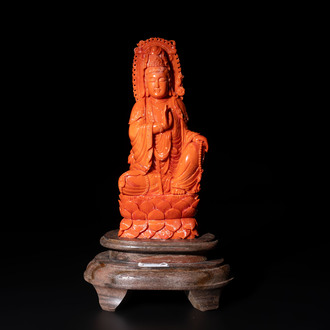 A fine Chinese red coral sculpture of Guanyin seated on a lotus throne on a wooden stand, 19/20th C.