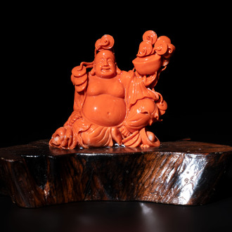 A Chinese red coral sculpture of a Milefo Buddha on wooden stand, 19/20th C.