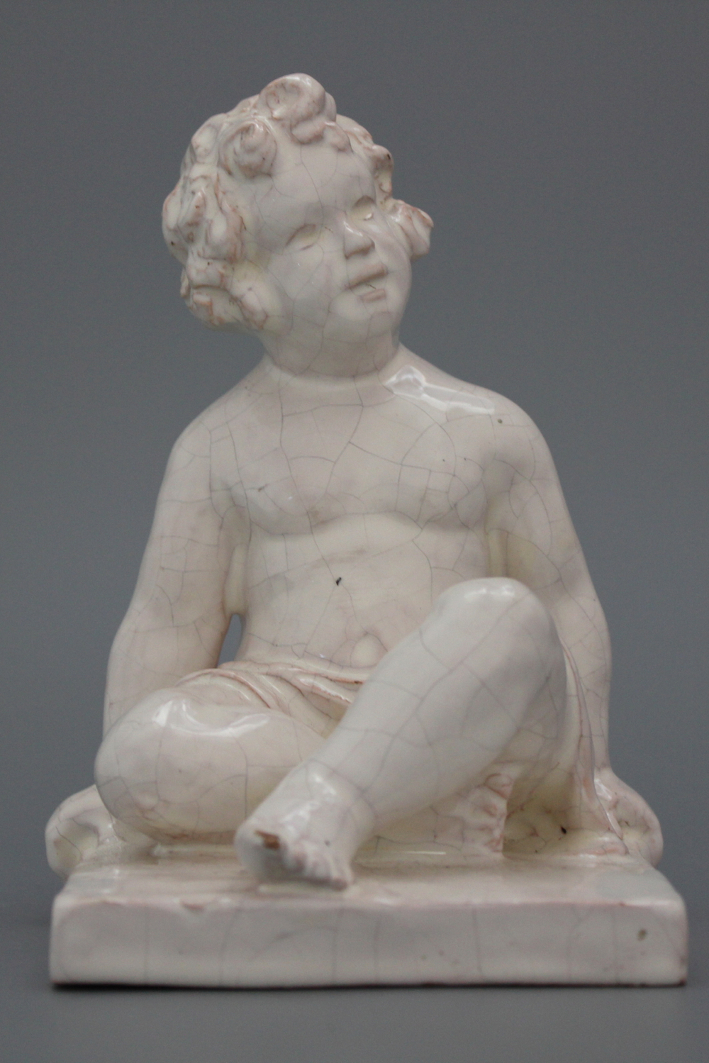 A pair of white faience book stands modelled as seated boys, Geo Martel, D&egrave;svres, early 20th C.
