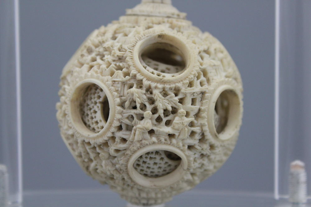 A Chinese ivory hanging puzzle ball on plexi stand, 19th C.