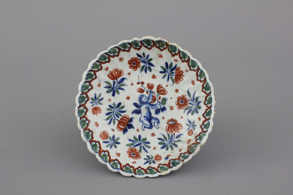 A Dutch Delft polychrome fluted saucer plate with a putto, early 18th C.