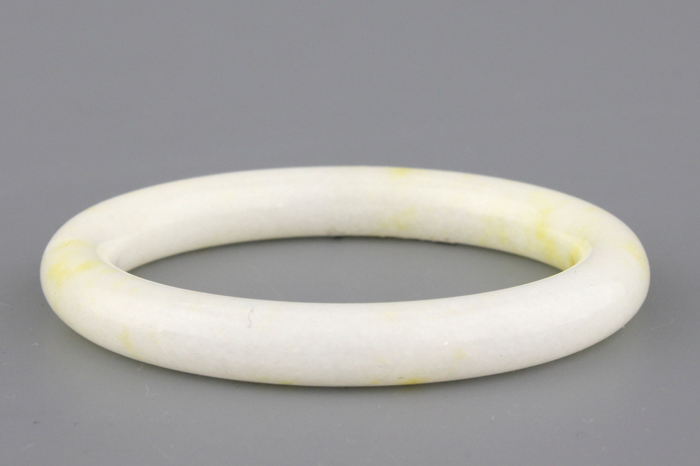 A white jadeite bangle with yellow incrustation, early 20th C.