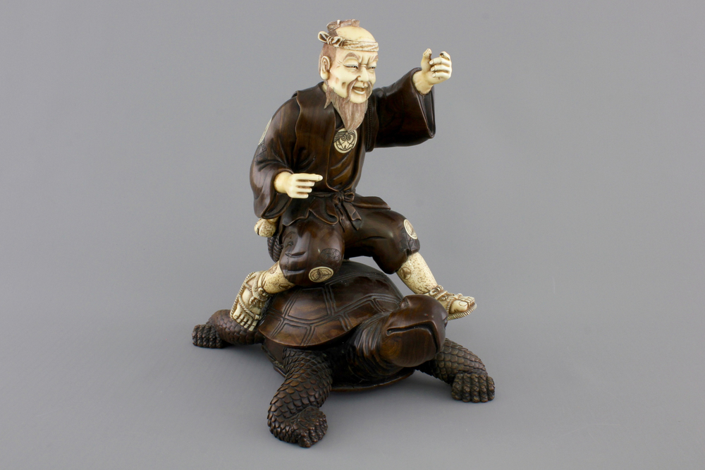 A signed Japanese carved ivory and wood figure of an immortal seated on a turtle, 19th C.