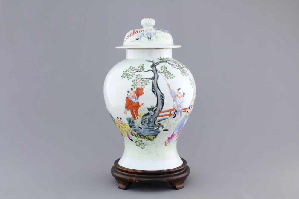 A Chinese famille rose porcelain vase with playing boys on a wooden stand, 19th C.