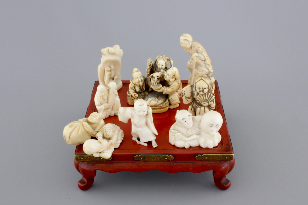 A set of 9 small Japanese ivory carvings, incl. netsuke, on a small red lacquer table, 19th/early 20th C.