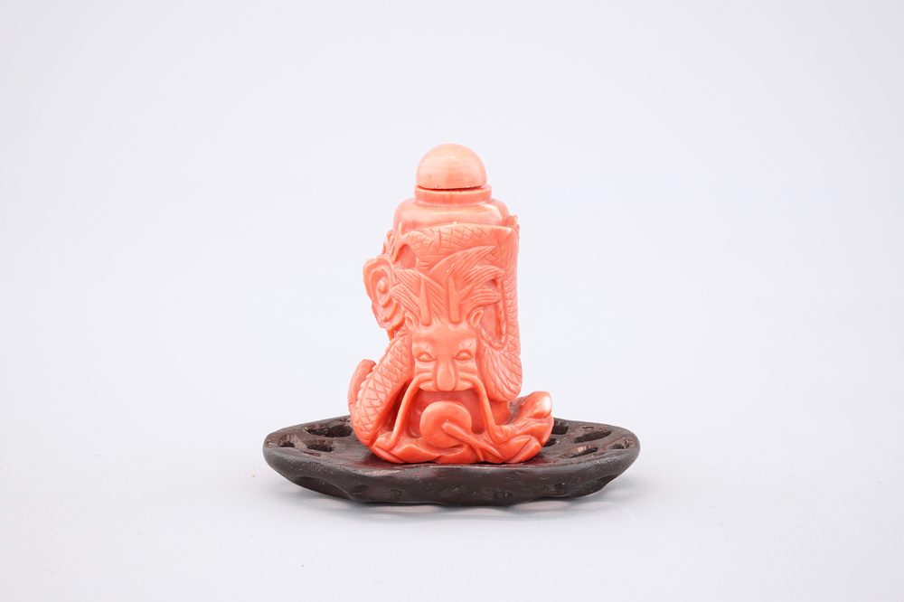 A Chinese carved red coral dragon snuff bottle on stand, 19th C.