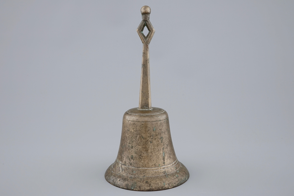 A tall bronze table bell with stylised handle, 16/17th C.