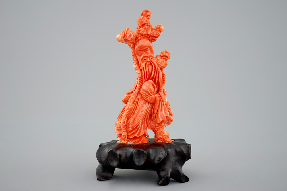 A Chinese carved red coral figure of Shou Lao on a wooden stand, 19/20th C.