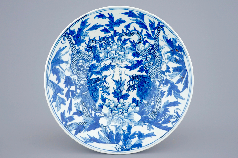 Un plat en porcelaine de Chine bleu et blanc &agrave; d&eacute;cor de dragons et pivoines, 19&egrave;me