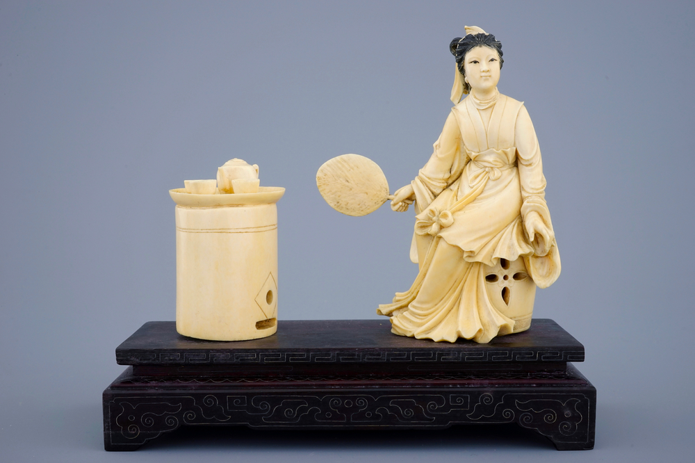 A Chinese carved ivory group of a lady near a tea table on a wood base, 19th C.