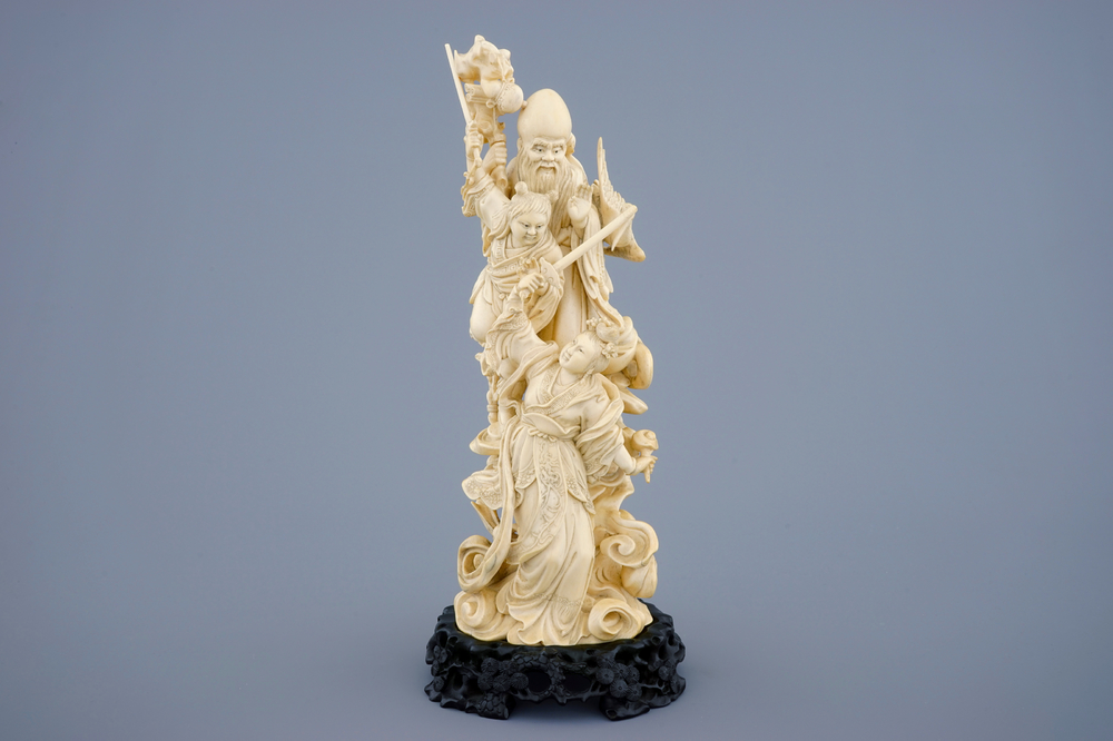 A Chinese carved ivory group of immortals on intricate wooden base, early 19th C.
