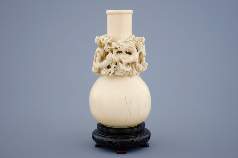 A Chinese carved ivory dragon vase on a wooden base, early 20th C.