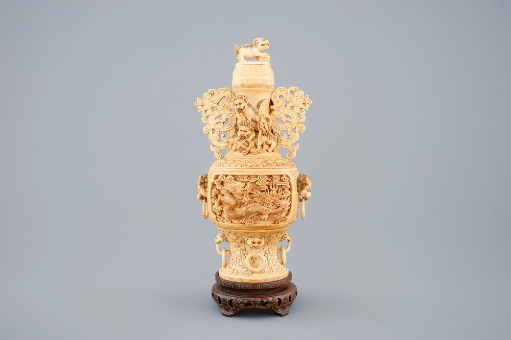 A Chinese carved ivory vase and cover on a wooden base, early 20th C.