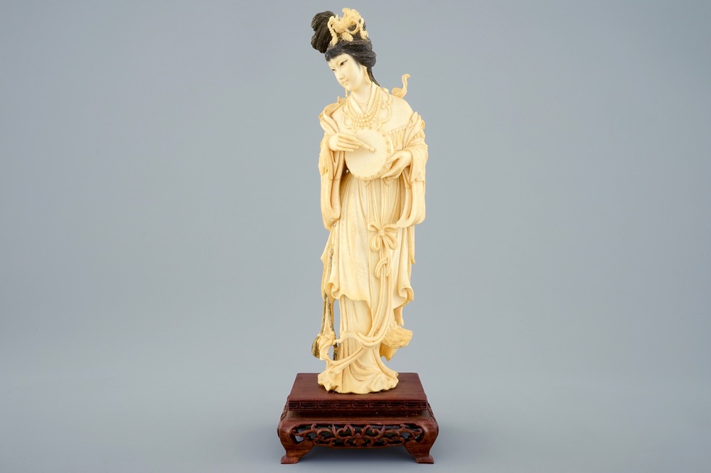 A Chinese carved ivory figure of a lady with hand drum on wooden base, early 20th C.